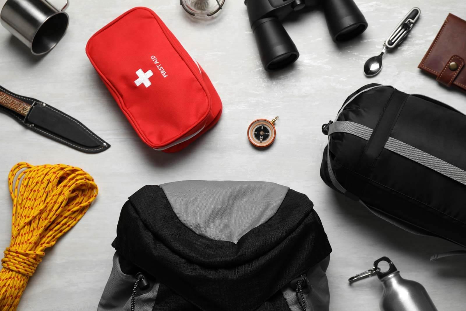 Essentials laid out, including a first aid kit, knife, rope, and backpack
