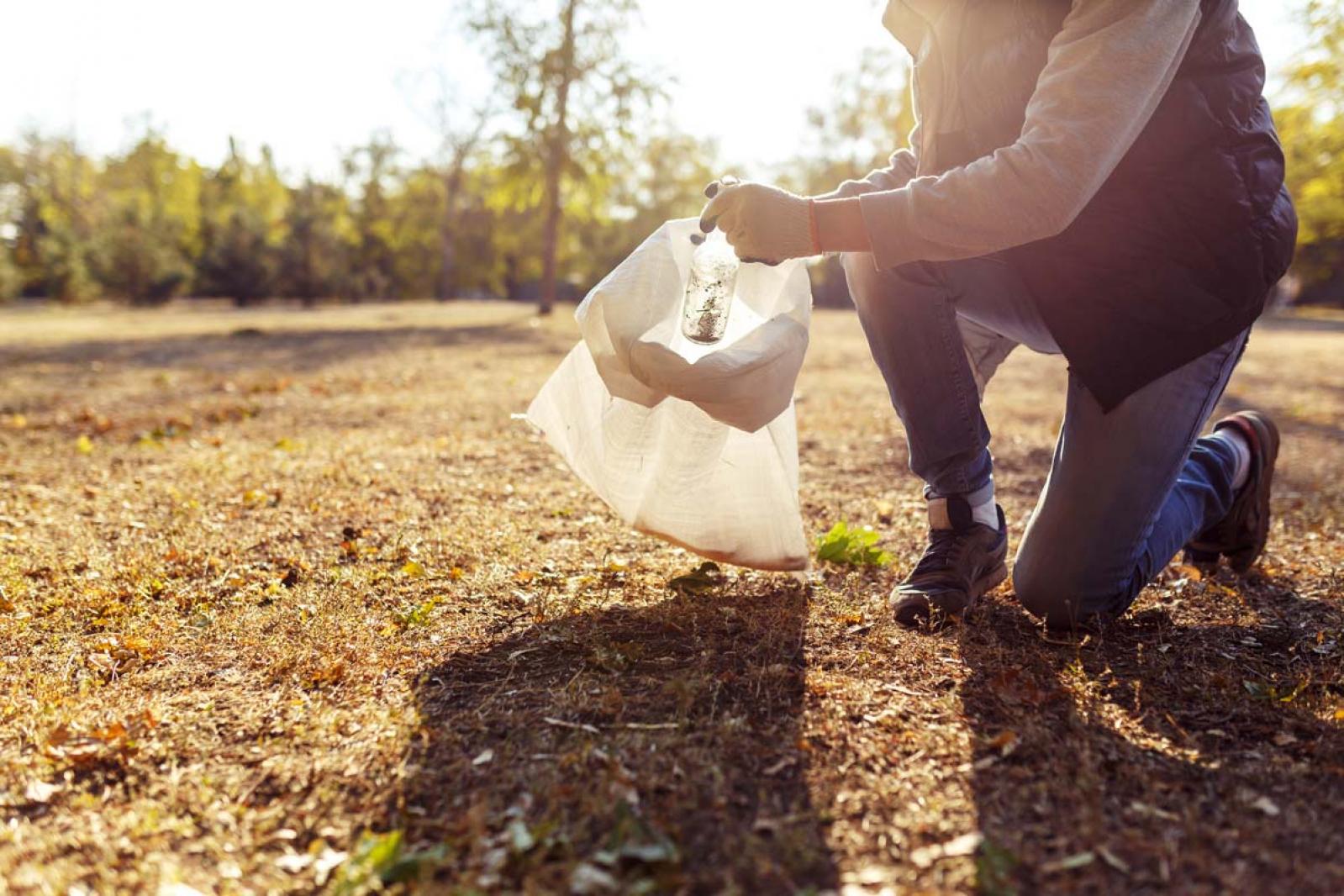 Man picking up trash in a field
