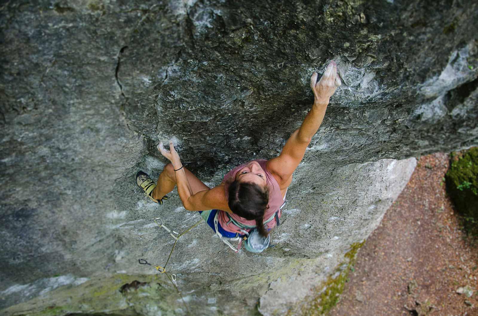 A rock climber climbing a wall outside from an aerial perspective