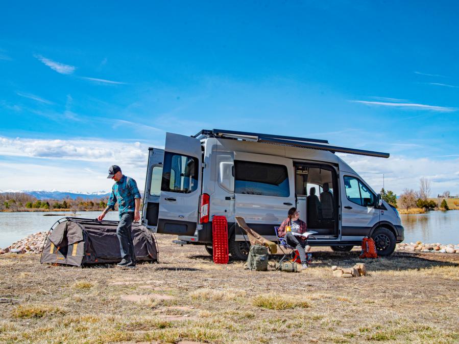 A group of friends hanging out by their Antero Adventure Van in front of a lake