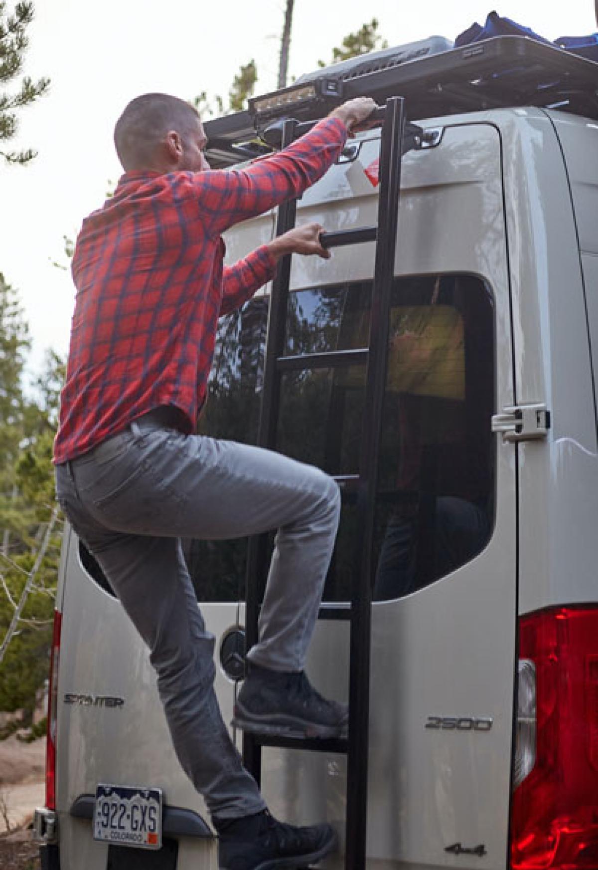 A man climbing up the ladder on the back of an Antero Adventure Van