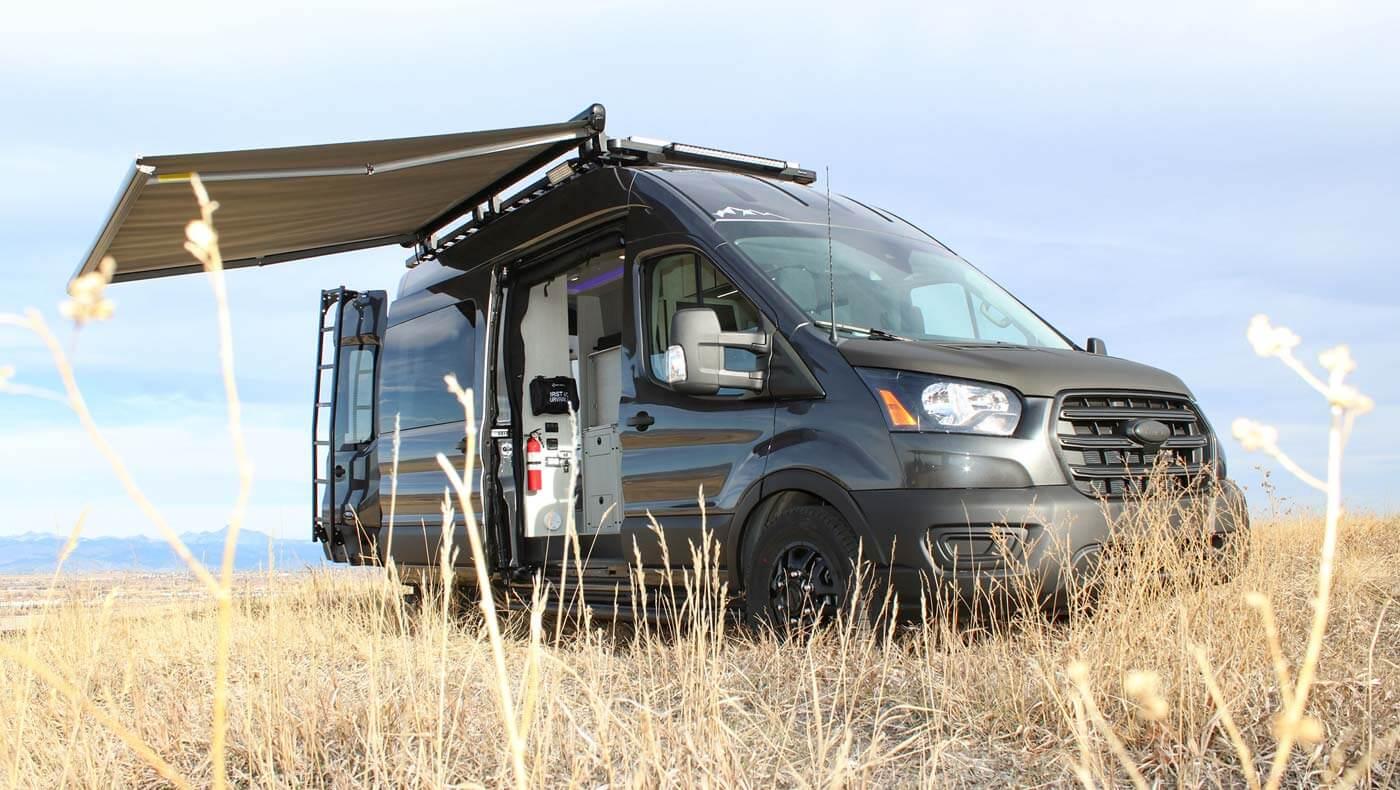 A Pikes Peak Antero Adventure Van in a field with its sun awning open